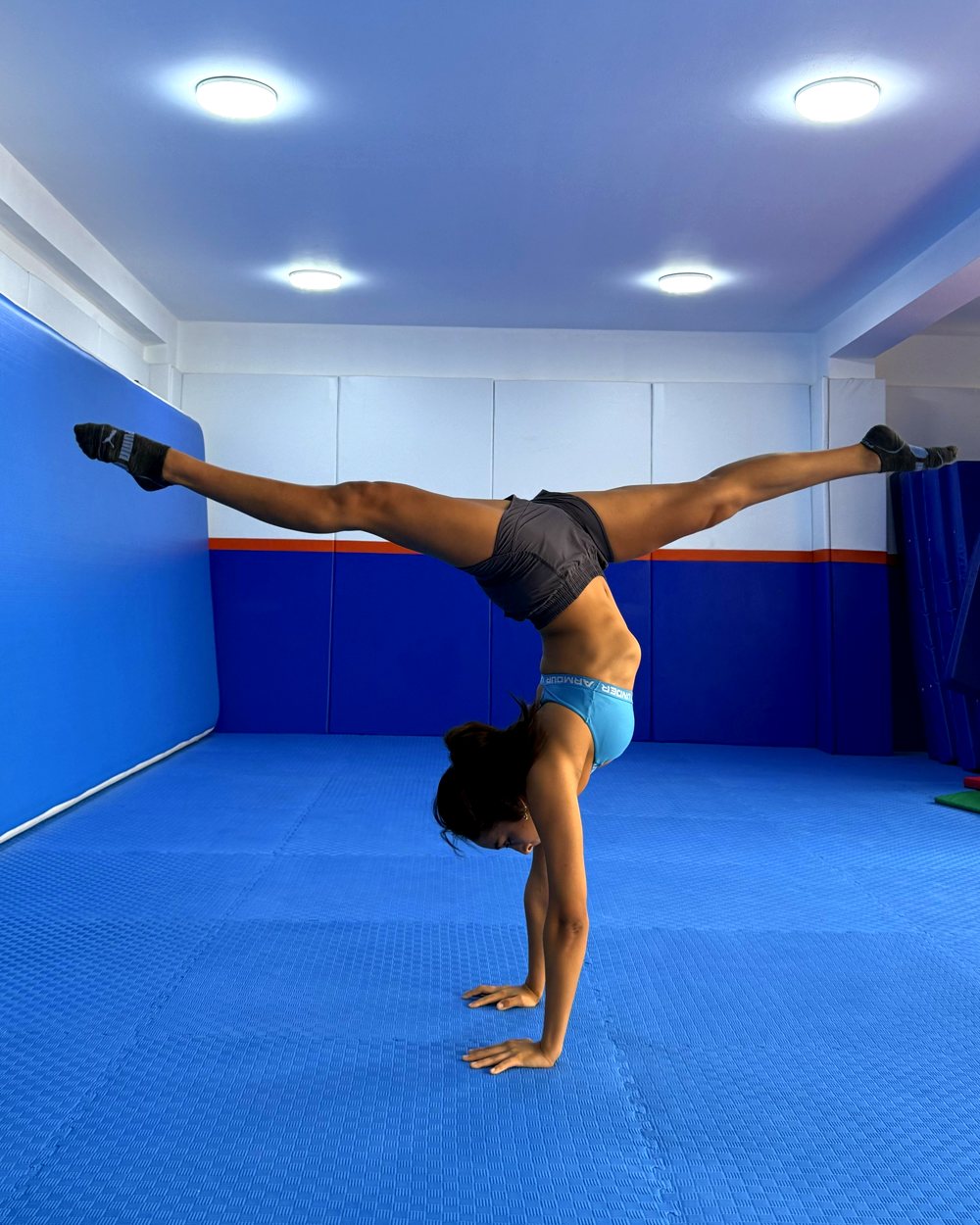 Alumna de Acroflex haciendo parada de manos con split en el salón